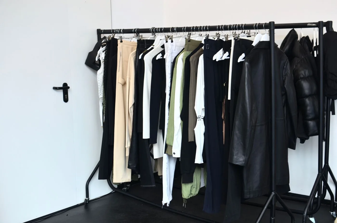 A clothing rack with mixed garments hanging in a bright room.